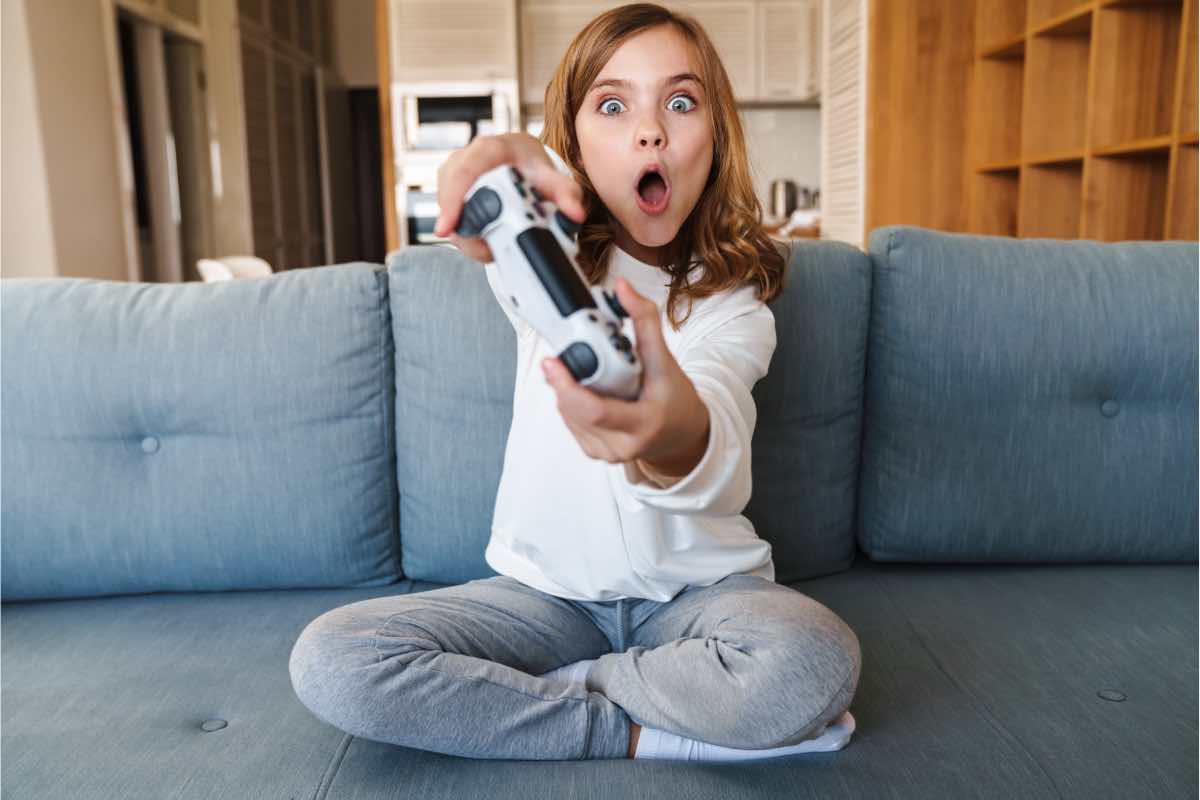 Bambina gioca alla Playstation 5 sul divano